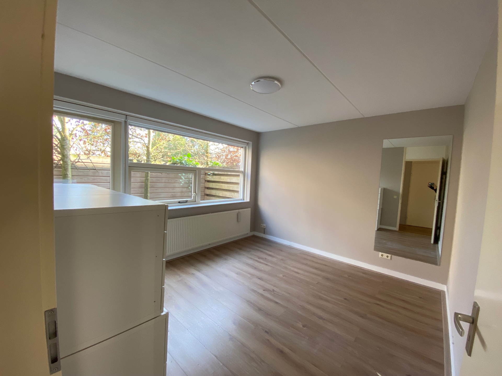 Slaapkamer op de begane grond met houten vloer en veel licht